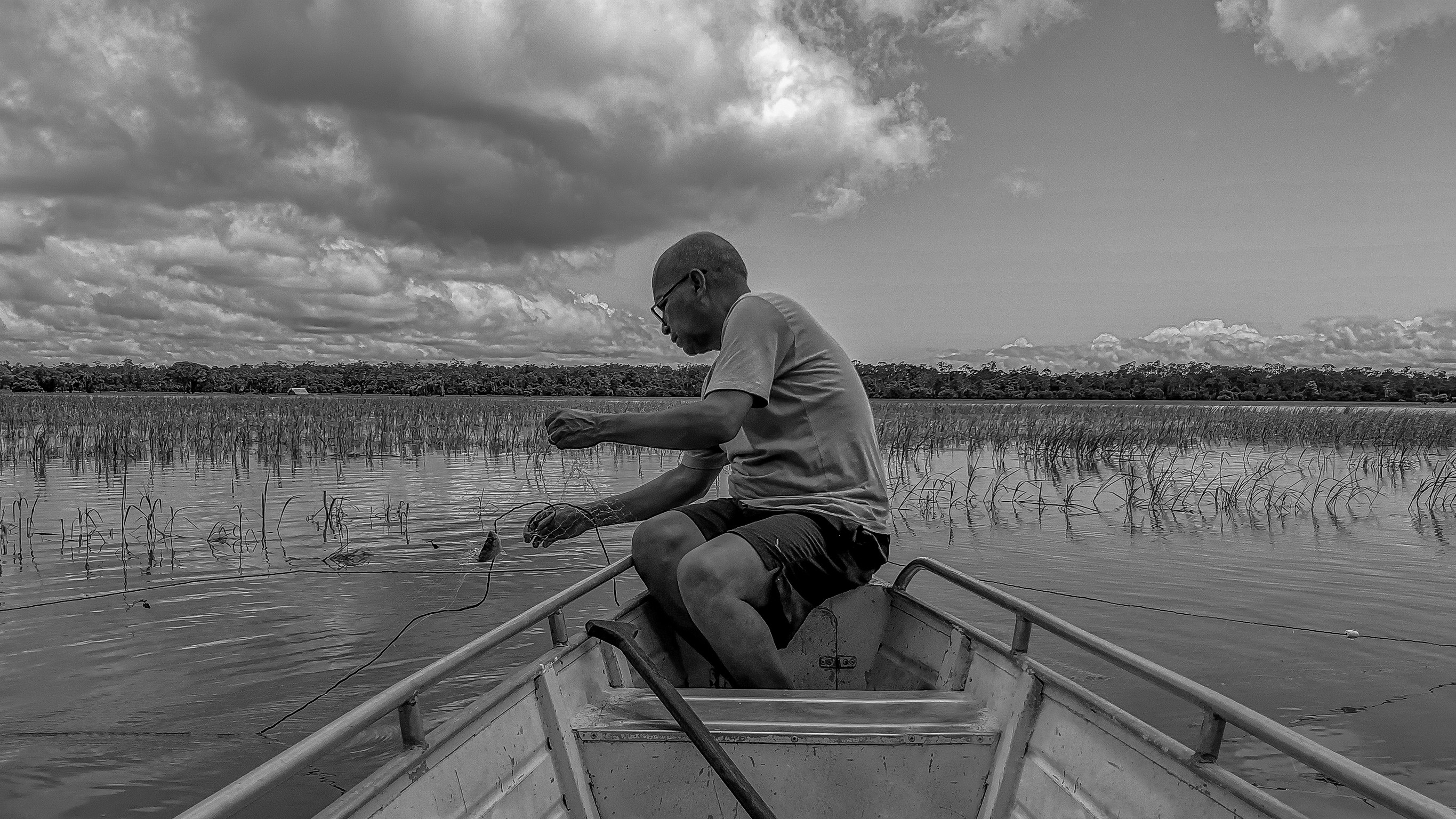 Native Amazonian Man Fishing In The Middle Of The Amazon Rainforest
