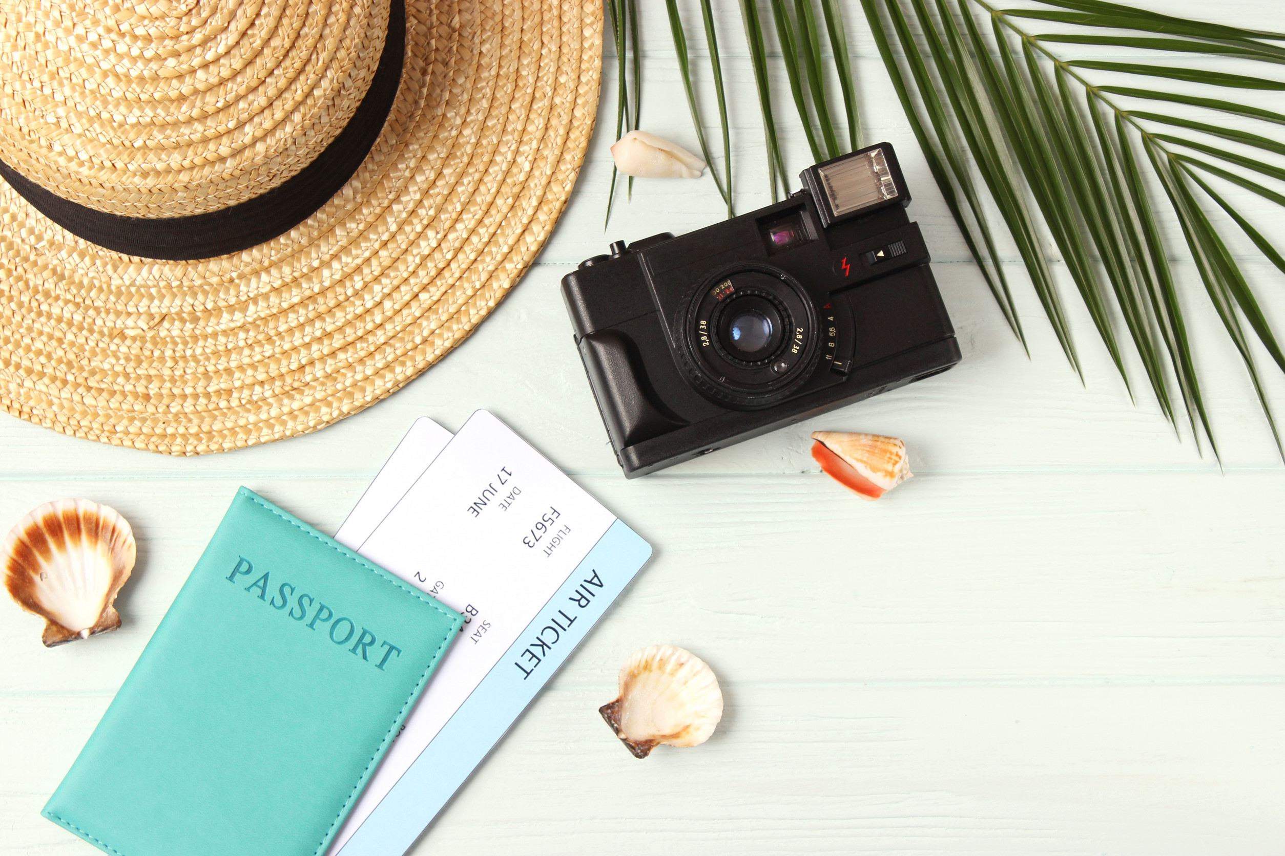 Travel Accessories And Tropical Leaves On A Colored Background Top View